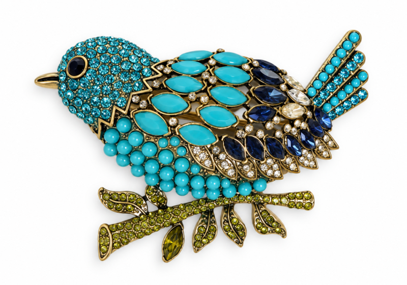 A Silvered metal bird brooch inlaid with multicoloured faceted glass cabochons.