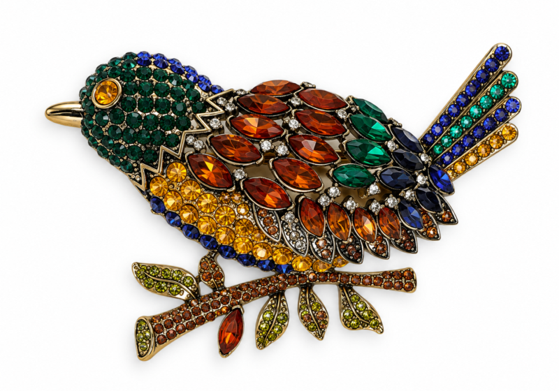 A Silvered metal bird brooch inlaid with multicoloured faceted glass cabochons.