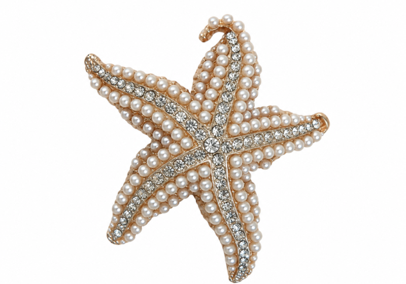 A Golden metal brooch of a starfish inlaid with round white glass "faux pearls" and clear faceted cabochons.