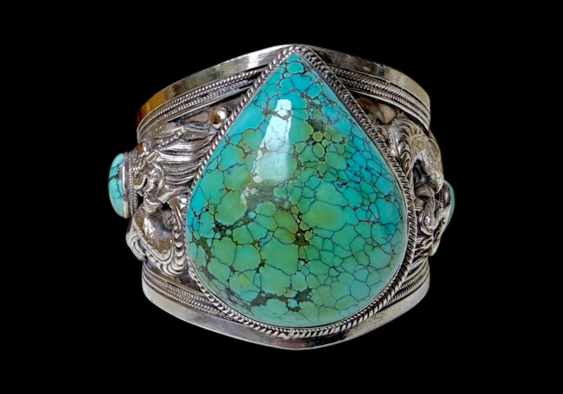 An Antique Tibetan Silver Open Cuff  Decorated With Two Dragons And A Large Turquoise Teardrop Cabochon And Two Smaller Oval Turquoise Cabochons